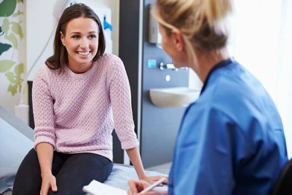 Female Patient And Nurse Have Consultation In Hospital Room