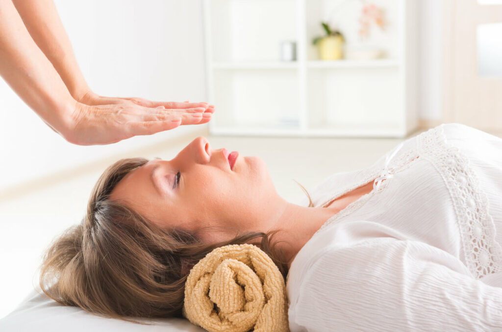 A woman lies on her back with her hands behind her head, relaxing on a surface.