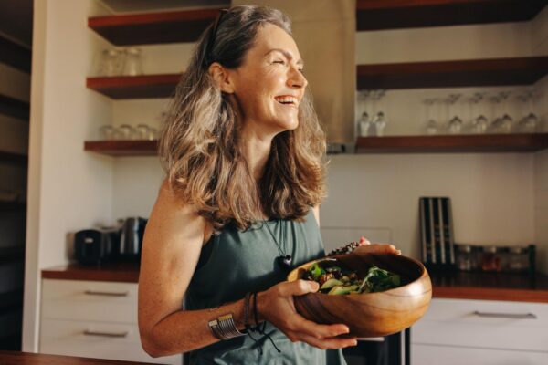 A woman smiling preparing a salad