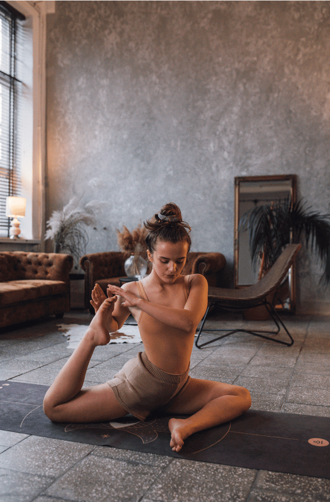 Woman performing a seated spinal twist yoga pose on a mat in a modern living room.