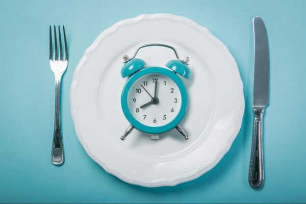 A clock on a plate with a fork and knife on the sides