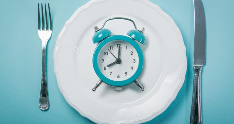 A clock on a plate with a fork and knife on the sides