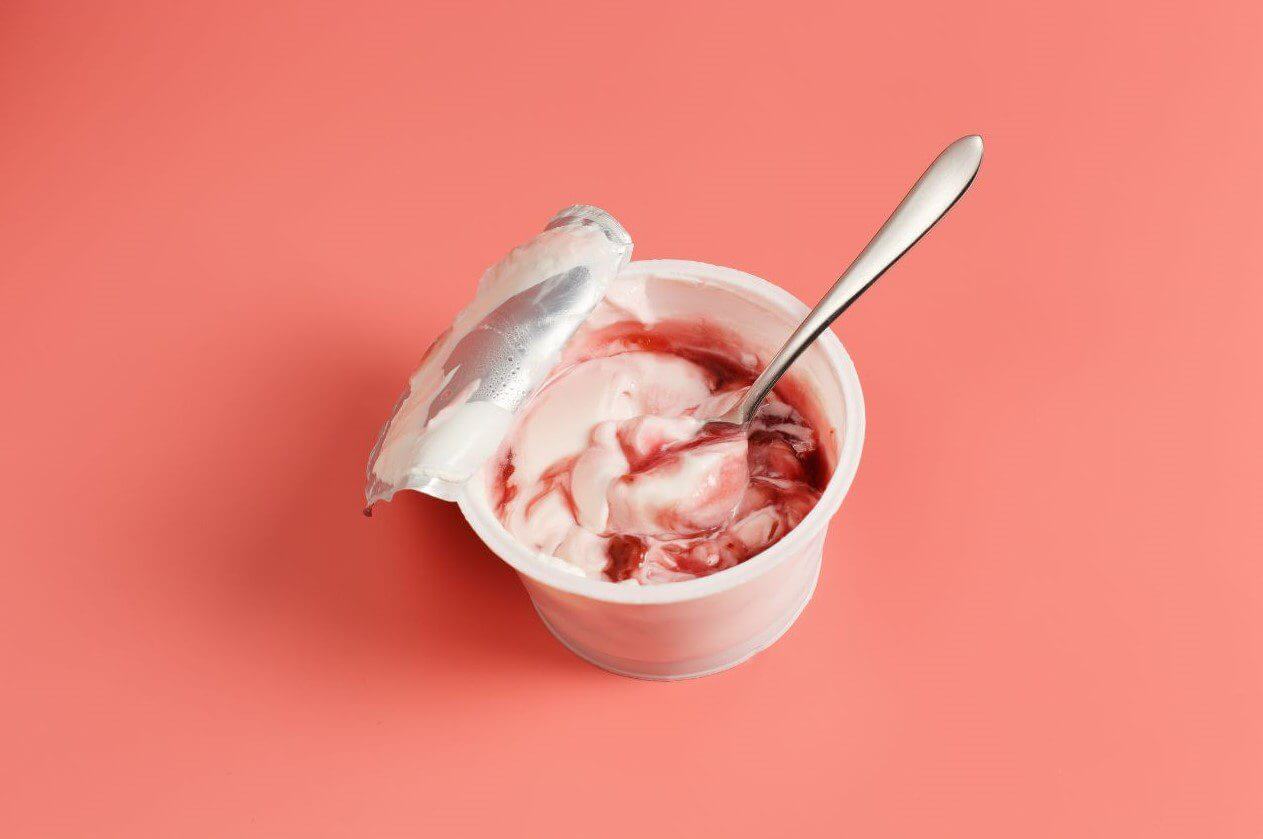 A Icecream container topped with a spoon, showcasing a simple snack ready to be enjoyed.