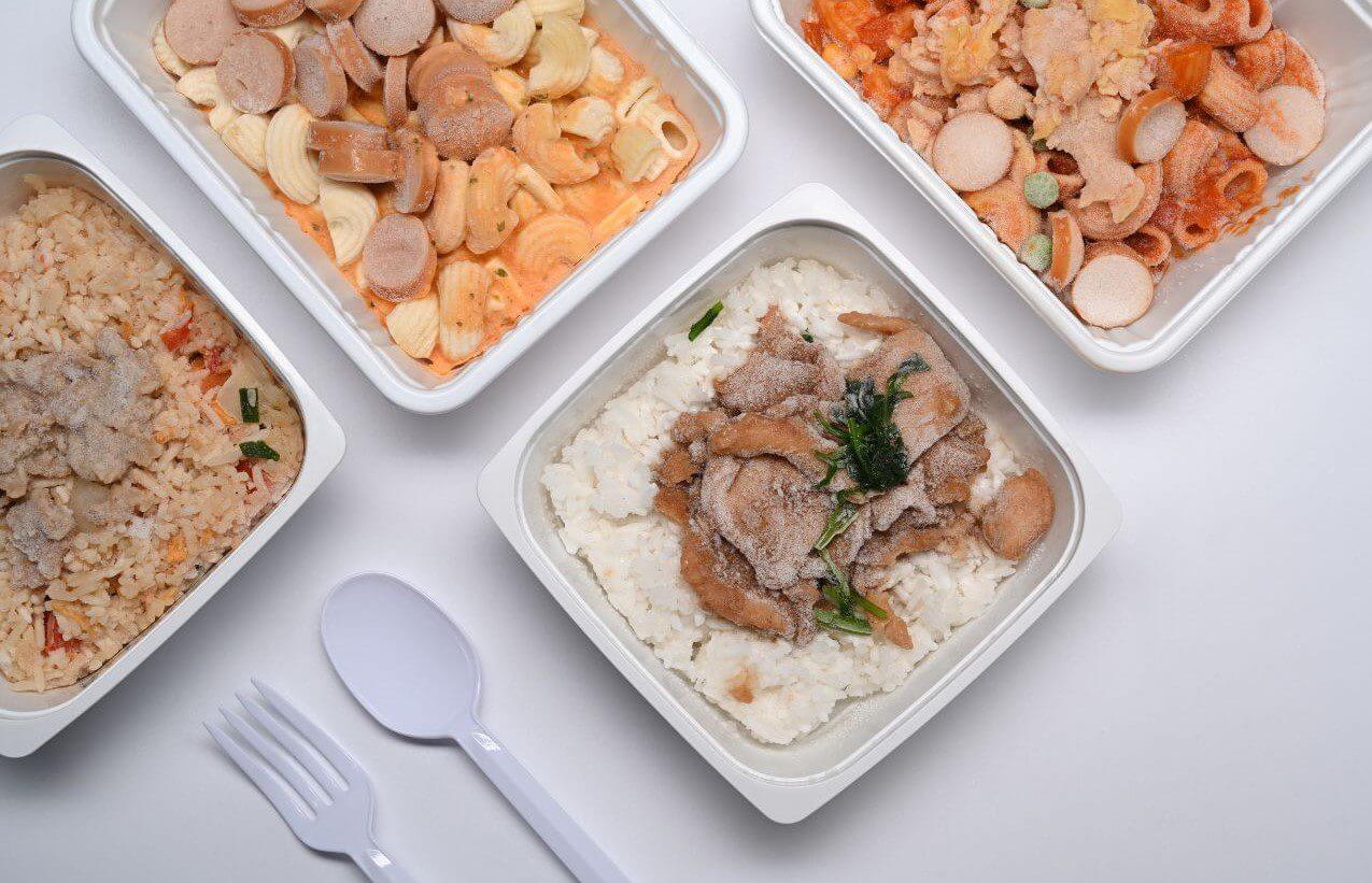 Four separate containers displaying rice, assorted meats, and mixed vegetables, highlighting a balanced meal presentation.