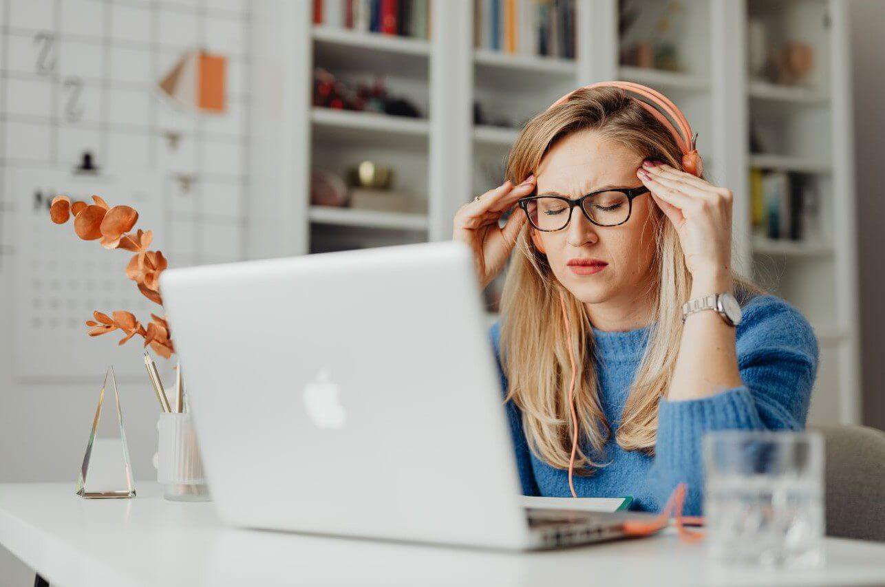 Woman wearing headphones sits at desk with laptop.