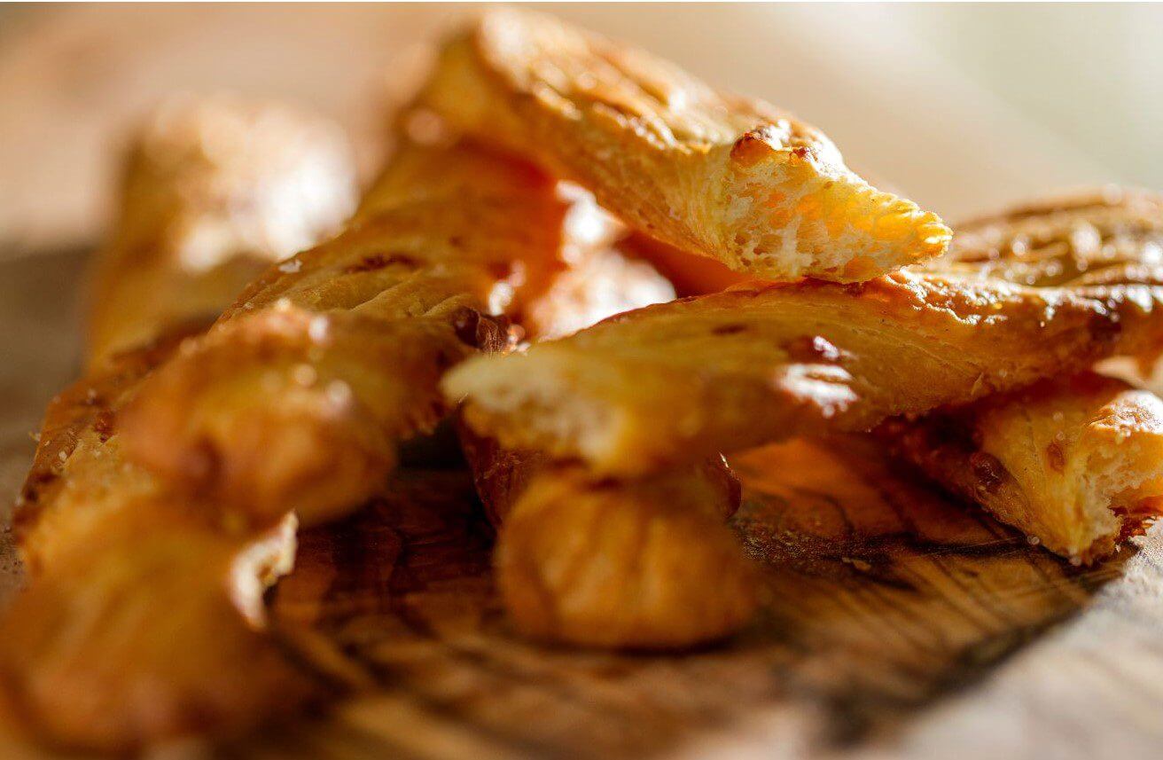 Close-up of breadsticks arranged on a rustic wooden table, showcasing their golden-brown texture.