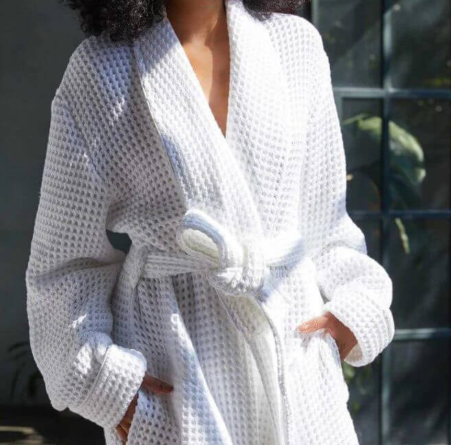 A woman in a white robe and hat stands gracefully, exuding a serene and elegant presence.
