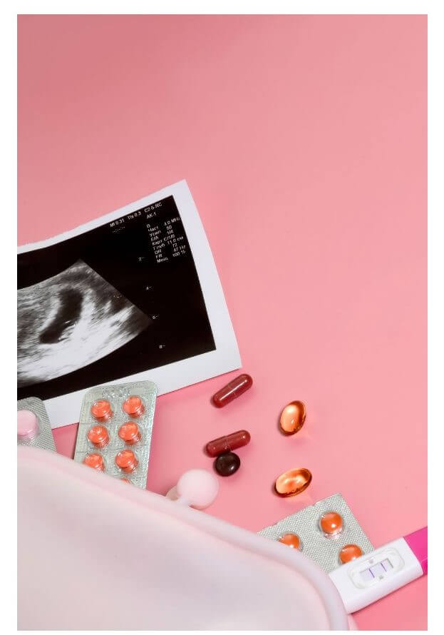 An ultrasound image is positioned next to various pills scattered on a pink surface.