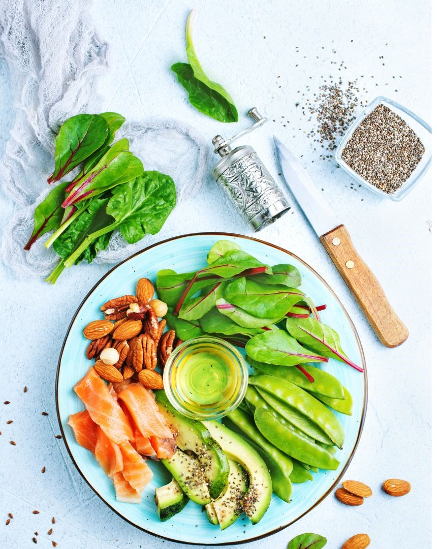 A blue plate holds smoked salmon, avocado, spinach, almonds, and chia seeds arranged artfully.