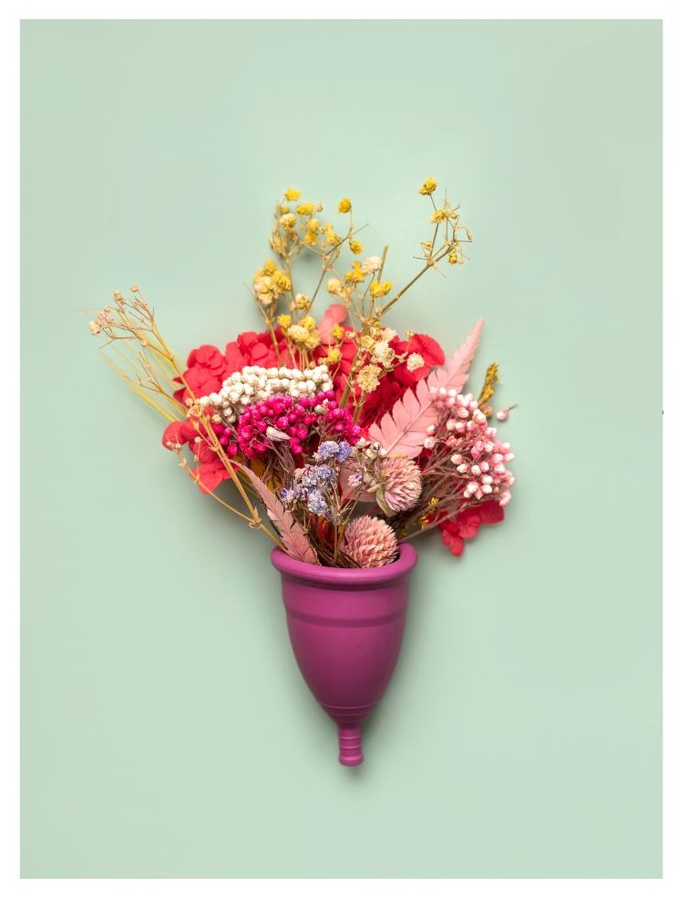 A purple container is filled with various colorful dried flowers against a pale green background.