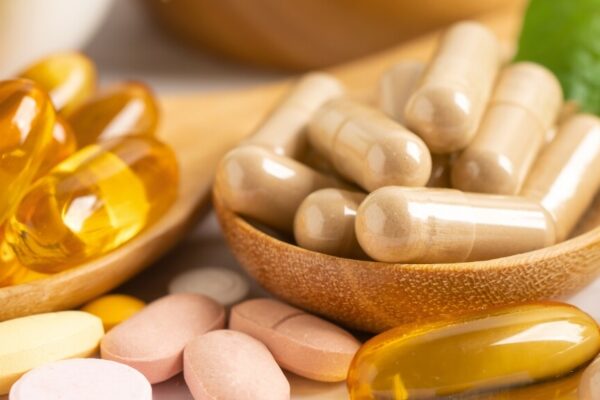 A collection of vitamins and supplements displayed in wooden bowls, showcasing a variety of colors and textures.