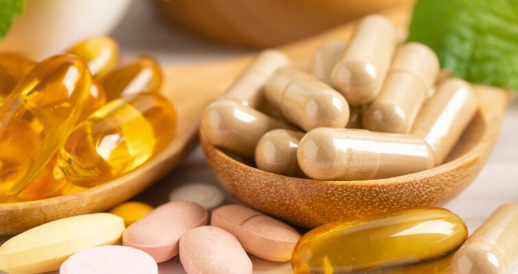 A collection of vitamins and supplements displayed in wooden bowls, showcasing a variety of colors and textures.
