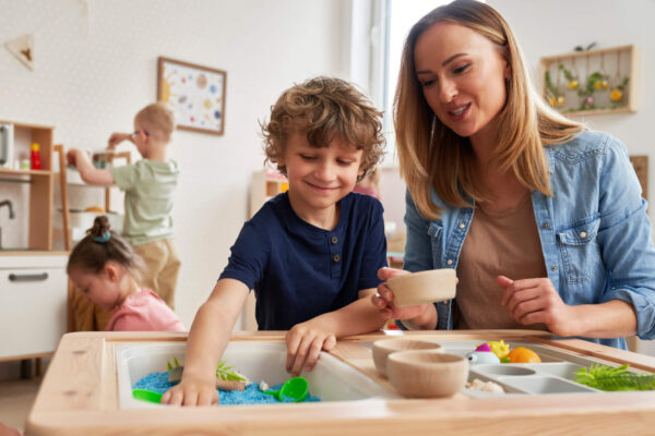 A woman and child joyfully play together at a wooden table, highlighting a nurturing interaction in a home setting.