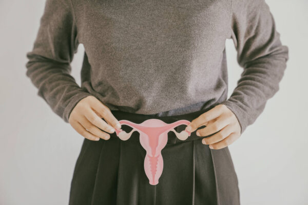 A woman gently holds a pink uterus in her hands, symbolizing women's health and reproductive rights.