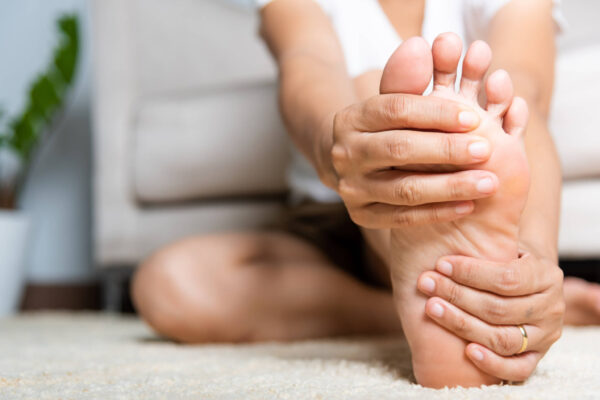 A woman is holding her foot in the air, demonstrating a stretch or exercise position.