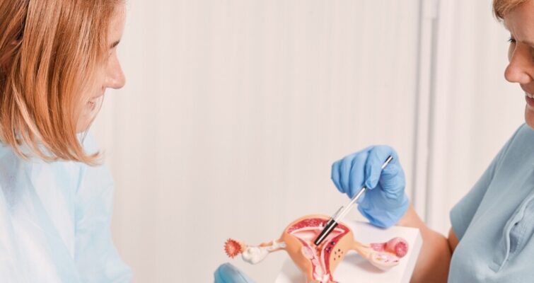 A woman holds a toothbrush while another woman observes her intently.