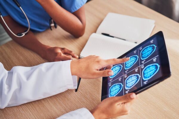 A doctor examines a tablet displaying an image of a brain, focusing on medical analysis and patient care.