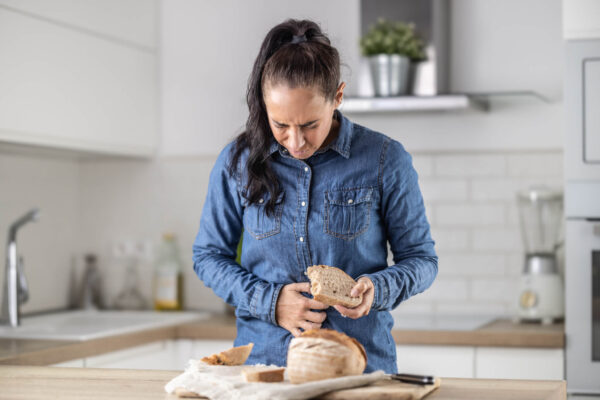 A woman holds a slice of bread, smiling as she prepares to enjoy her meal.