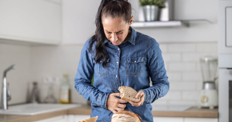 A woman holds a slice of bread, smiling as she prepares to enjoy her meal.