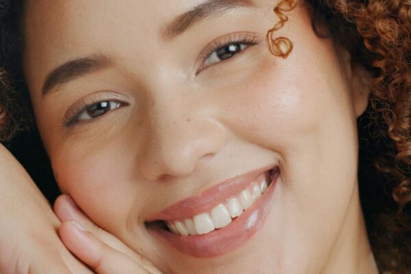 A woman with curly hair smiles warmly, showcasing her joyful expression.