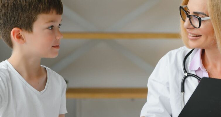 A woman speaks to a boy in a white shirt, highlighting a moment from ADHD therapy in Atlanta.