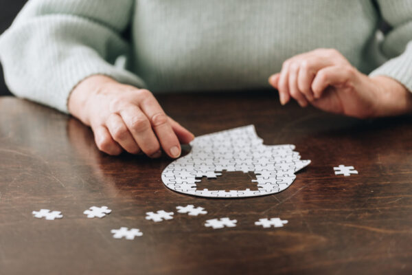 A woman assembles puzzle pieces on a table, symbolizing the complexities of Alzheimer's genetic testing.