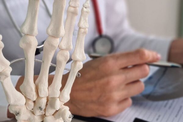 A doctor examines a skeleton model, highlighting anatomy relevant to arthritis treatment in Atlanta.
