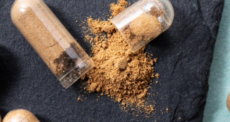 Close-up of capsules filled with brown powder, showcasing their texture and color against a neutral background.