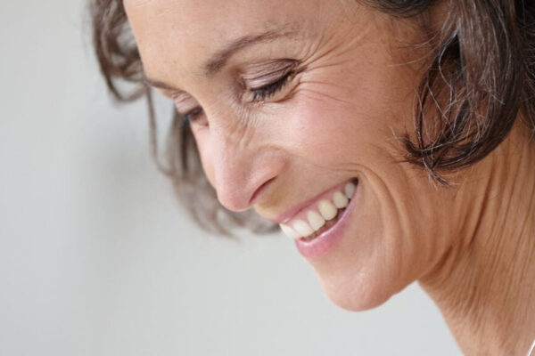 A woman smiling while looking at her phone, representing BioIdentical Hormone Therapy options in Atlanta.