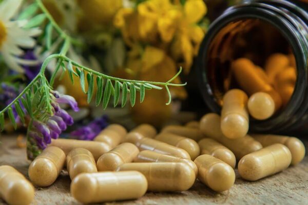 A bottle of pills beside a bouquet of flowers on a wooden table, suggesting a theme of health and wellness.