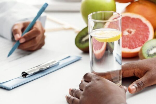 Two doctors reviewing notes on a clipboard beside a glass of water, symbolizing expert guidance in diabetes nutrition.