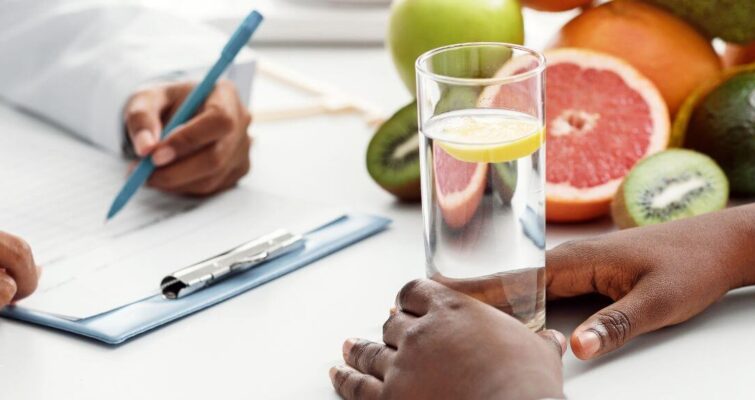 Two doctors reviewing notes on a clipboard beside a glass of water, symbolizing expert guidance in diabetes nutrition.