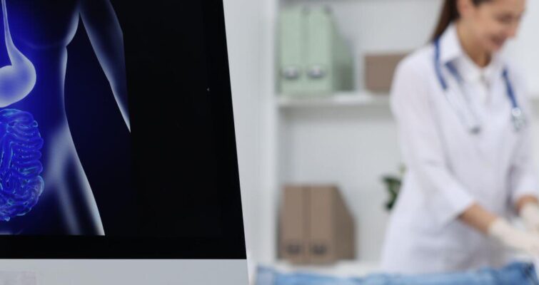 A woman sits in a chair, viewing a computer screen displaying a stomach, related to Digestive Disease Clinic options in Atlanta.