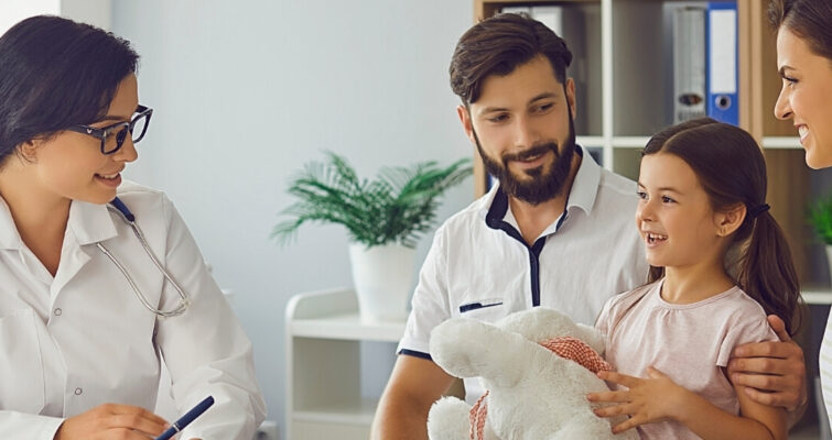 A doctor sits with a family in a consultation room, discussing health matters in a supportive environment.