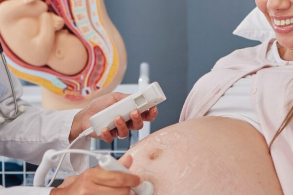 A pregnant woman receives a medical examination from her doctor in a healthcare environment.