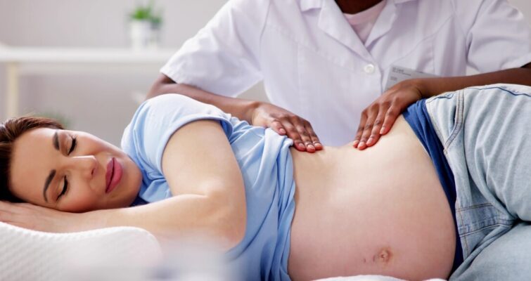 A pregnant woman relaxes while receiving a soothing massage in a serene setting.
