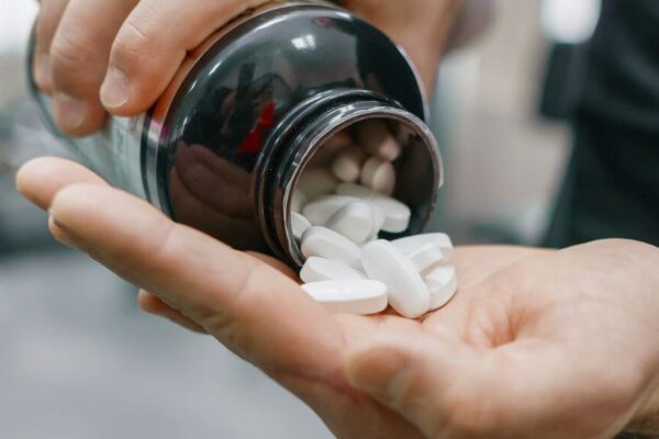 A person holding a pill bottle filled with holistic weight loss supplements for natural slimming support.