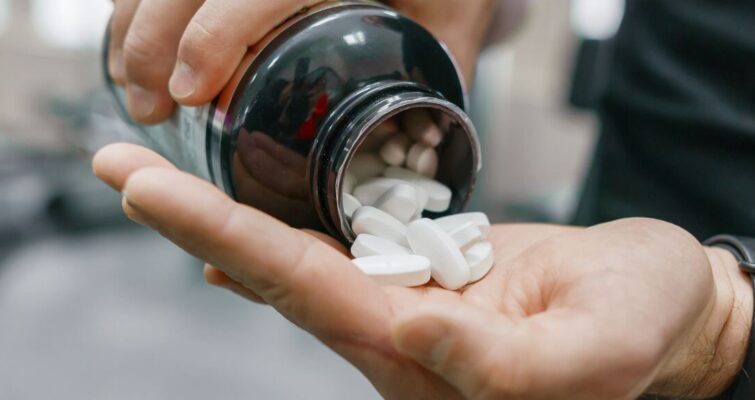A person holding a pill bottle filled with holistic weight loss supplements for natural slimming support.