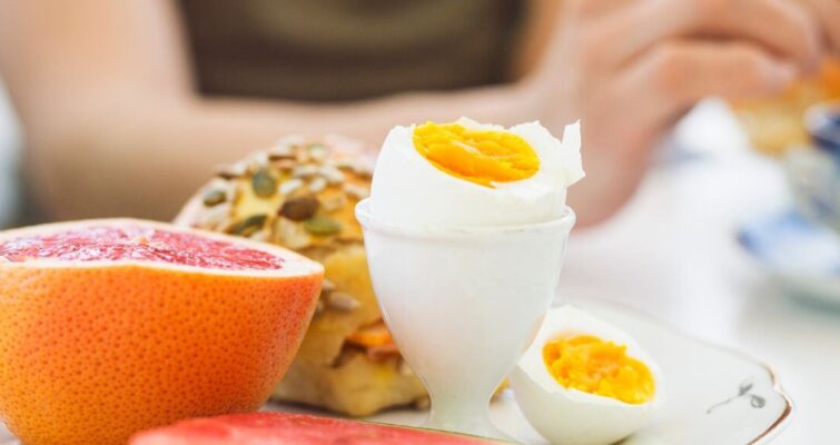 A plate featuring a cooked egg, a sliced orange, and watermelon, representing a hormone balancing diet for women.