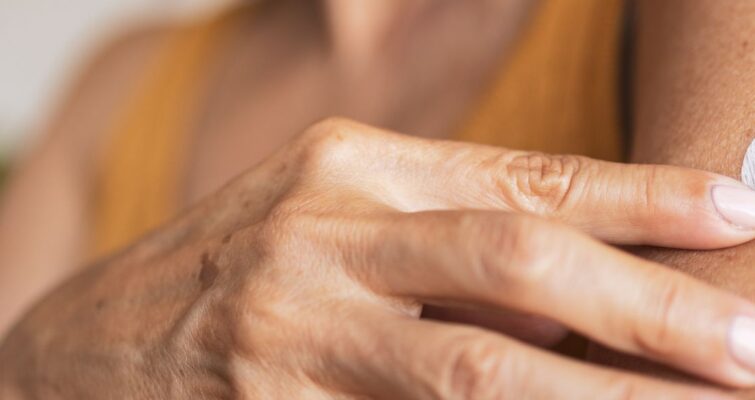 A woman applies a hormone replacement therapy patch to her arm, highlighting options available in Atlanta.
