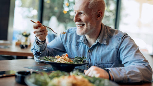 A man enjoys a fresh salad while seated at a restaurant table from cholesterol.