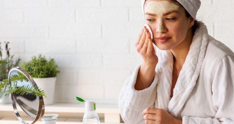 A woman in a bathrobe holds a face mask, representing a skincare routine for women in their 30s.