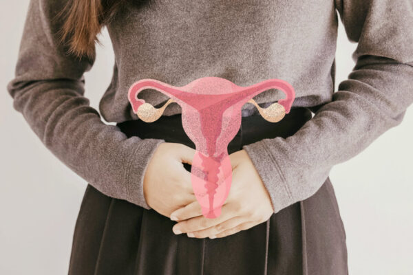 A woman holds her stomach, with a pink uterus graphic, symbolizing awareness of PCOS types.