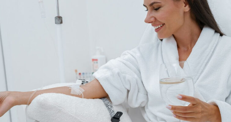A woman in a bathrobe holds a glass of wine, suggesting relaxation and self-care amidst Vitamin C IV therapy options in Atlanta.