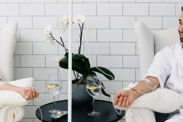 A man and woman in white robes relax together in a bathtub, suggesting a serene wellness experience.