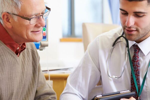 A doctor discusses holistic health approaches with an older man in a clinical setting.