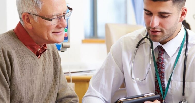 A doctor discusses holistic health approaches with an older man in a clinical setting.
