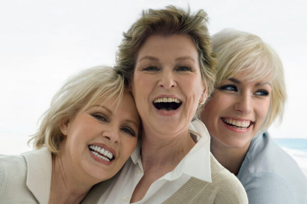 Three women are joyfully smiling and laughing together, showcasing a moment of friendship and happiness.