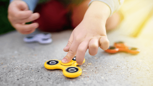 A child focused on spinning a fidget spinner, illustrating a tool often used for managing ADHD and anxiety.