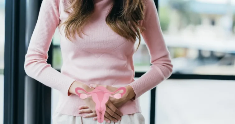 A woman holds her stomach while grasping a pink object, symbolizing issues related to PCOS and endometriosis